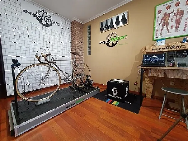 Vista general del estudio: bicicleta sobre el rodillo y pared de sillines de prueba